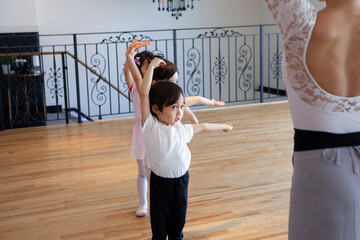 先生に習って振りを覚えるバレエダンサーの幼い少年少女