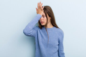 young adult pretty woman raising palm to forehead thinking oops, after making a stupid mistake or...