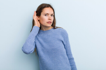 young adult pretty woman looking serious and curious, listening, trying to hear a secret...
