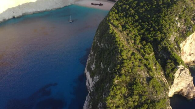 Aerial drone view of the Navagio beach (Shipwreck beach) on the Ionian Sea coast of Zakynthos, Greece. Rocky cliffs, alone boat, beach without people, sunset, sunrise.