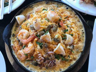Sizzling seafood fried with eggs and batter served on hot plate in Thailand.