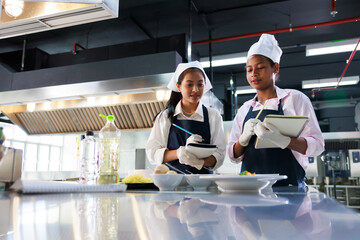 take note on book. Cooking class. culinary classroom. group of happy young woman multi-ethnic students are focusing on cooking lessons in a cooking school.