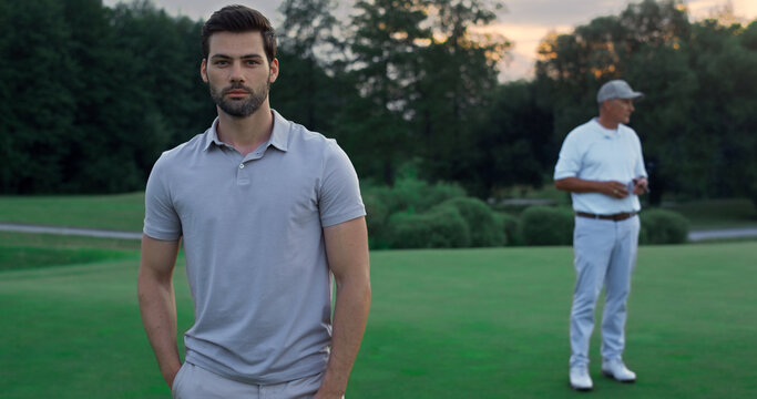 Focused model enjoy golf on sport team outdoors. Two players standing on course.