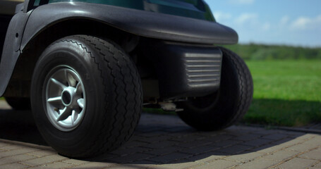 Fototapeta na wymiar Professional golfing cart wheels at golf club road. Sport buggy car at summer.