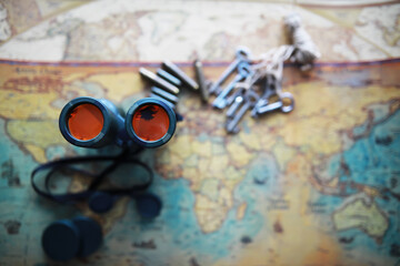 Fototapeta premium Binoculars and reflection in lenses. Map and shells background.
