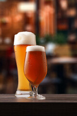 Two glasses of beer on counter in pub.