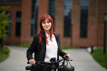 Fototapeta na wymiar Portrait of businesswoman commuter on the way to work with bike looking at camera, sustainable lifestyle concept.
