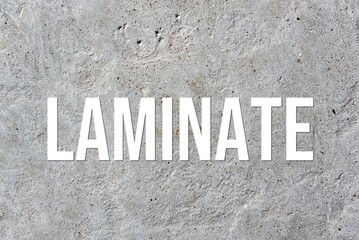 LAMINATE - word on concrete background. Cement floor, wall.