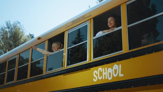 Two multiethnic pupils looking out school bus window. Teenagers ready to studies