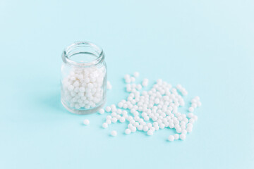 Homeopathic pills and a glass bottle on a blue background. Homeopathic medicine	