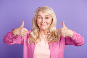 Photo of mature cheerful woman show fingers thumbs-up approve perfect select isolated over purple...