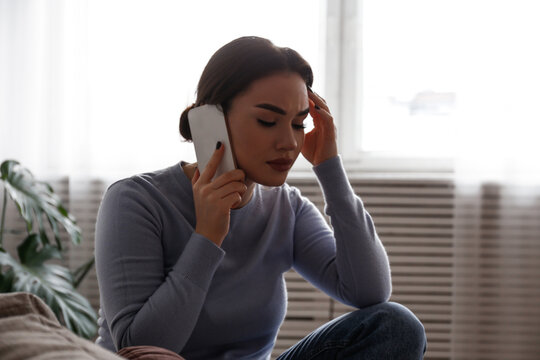 Portrait of upset young woman on the phone with a doctor receiving bad news. Sad female frowning, about to cry. Copy space for text, white wall background, close up.