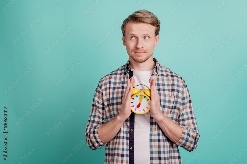 Wall mural Curious minded thoughtful guy hold alarm clock look empty space think ideas contemplate punctuality