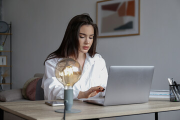 Young beautiful brunette woman at the office, copywriter typing a new text on her laptop. Portrait...