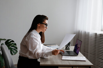 Young smart looking woman wearing glasses at the office, lawyer doing the paperwork. Portrait of...