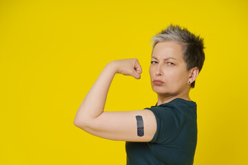 Health is power senior woman with grey hair showing nude bicep, shoulder with band aid or plaster...