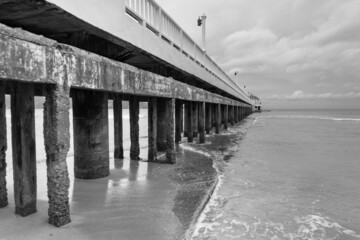 Black and white image of Side view of pier at the beach at sunset time.Thailand.