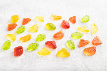 Various jelly candies on gray concrete background. close up, side view.