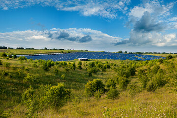 solar panels station, hills and bushes under blue sky on summer landscape