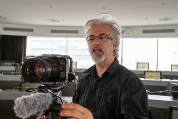 Film director with the film camera ready to start work inside a filming studio.