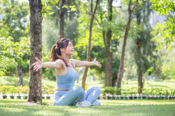 Sport woman breathing deeply fresh air with arms raised outdoor in park