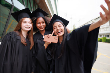 student wearing gown and making photo by smartphone  graduating. Happy graduate success and...
