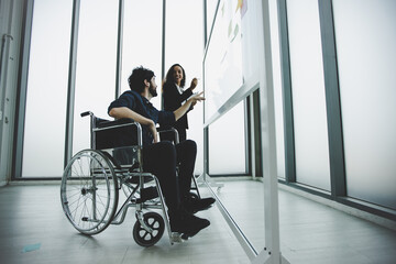 young disabled businessman wearing in wheelchair working and discus with colleague, planning and...