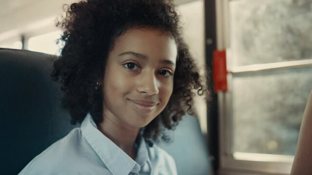 African American schoolgirl looking camera in school bus close up. Girl posing.