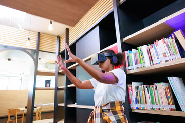 Fototapeta na wymiar VR headset library. Young teen girl student training and learning with VR virtual teality headset in school library.