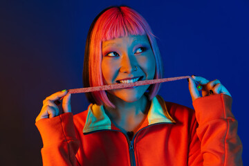 Asian girl with pink hair making fun while eating chewing marmalade