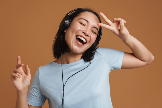 Young Asian Woman In Headphones Dancing While Listening Music