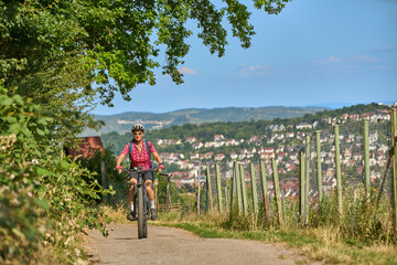 Nice active senior woman with electric mountain bike on a tour in the hills above the city of...