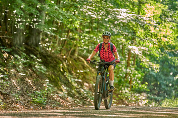 Naklejka premium nice active senior woman riding her electric mountain bike in the green city forest of Stuttgart, Germany