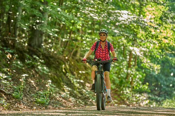 nice active senior woman riding her electric mountain bike in the green city forest of Stuttgart, Germany