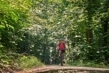 Obraz premium nice active senior woman riding her electric mountain bike in the green city forest of Stuttgart, Germany