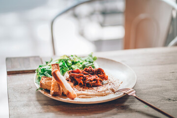 Tasty hummus on a plate with vegetables and bread on a wooden table in a restaurant outdoors. Mediterranean snack, vegetarian healthy food concept. European vegan dish. Hoummous