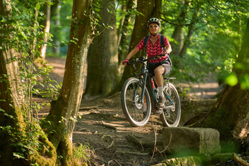 nice active senior woman riding her electric mountain bike in the green city forest of Stuttgart,...