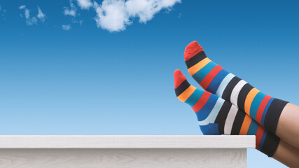 Creative person with multicolor sock relaxing with feet up