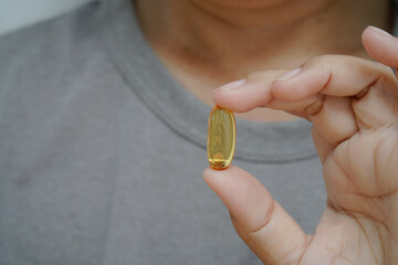 Female holding with Omega 3 fish oil capsule.