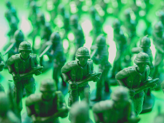 Small toy soldiers of green color in battle in front of green background.