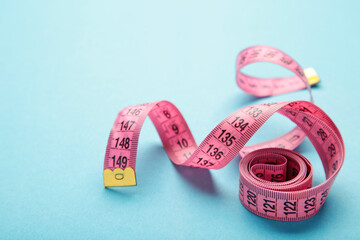 Pink plastic measure tape with metric scale over on blue background.