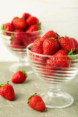 Strawberries in glass cups on light background. Vertical photo