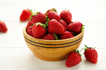 Ripe strawberries in wooden bowl on white background. Space for text