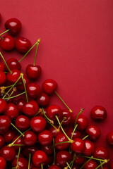 Sweet cherry on red background. Top view. Flat lay. Vertical photo