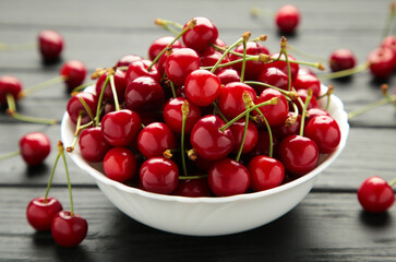 Obraz na płótnie Canvas Fresh sweet cherries bowl on black background, top view