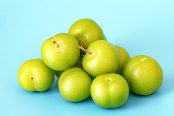 Harvest of green and sour Turkish plum, a popular delicacy refreshing in hot weather. Juicy fruit cheerfully crunches and quenches thirst. On light blue background