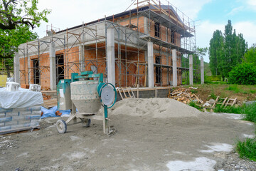 Concrete mixer in a site close-up. construction site with equipment and building. House in...
