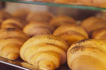 Fresh baked croissants. Fresh croissants in showcase. Homemade pastry. Bakery in market stall. Bread selling. Breakfast concept. Tasty croissants in morning cafe. Homemade food. 