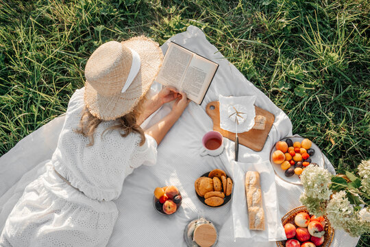 Woman read book on picnic in field.