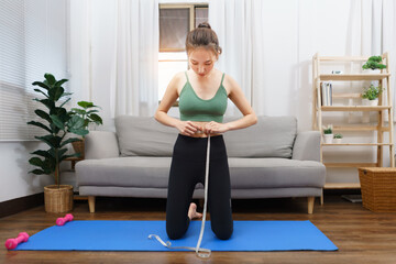 Obraz premium Healthy and weight loss concept, Young Asian woman is measuring her waist with tape measure